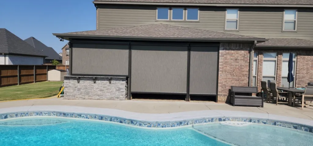 Motorized retractable screens closed beside a swimming pool on a brick home in Northwest Arkansas
