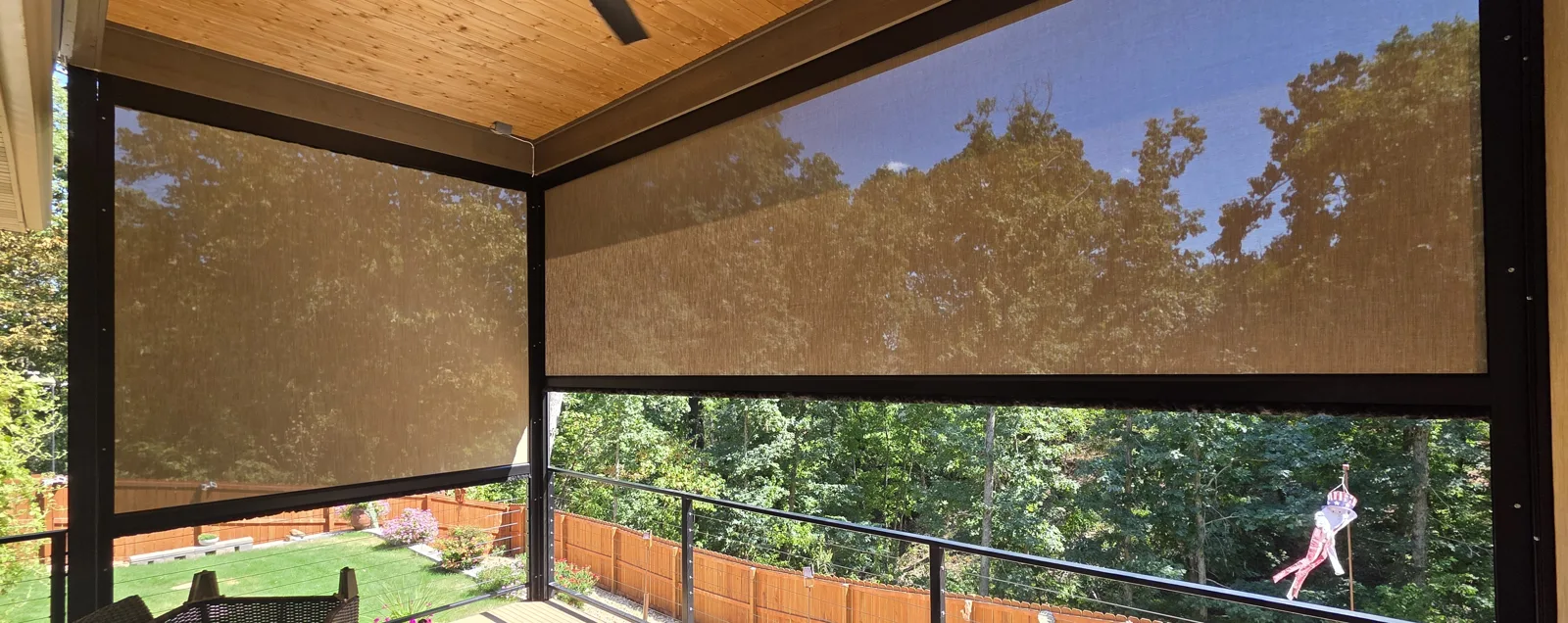 Motorized retractable screens on a covered deck in Latheron, Bella Vista, Arkansas, one lowered over the wooded view