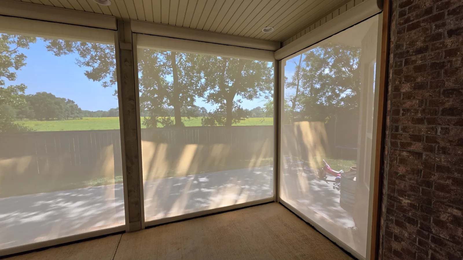 Inside view of a light see-through screen across a covered patio looking out to a field in Brighton Cottages, Bentonville, Arkansas