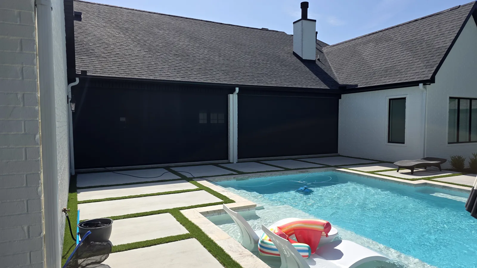 Two black screens closed across the back of a house with a gray roof, beside a pool, retractable screens for homes in Creekside, Centerton, Arkansas