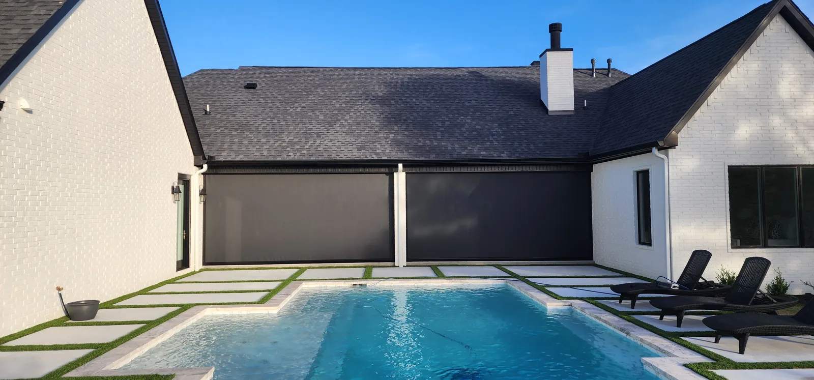 Two dark gray screens closed on the back of a white painted brick house, beside a pool, retractable screens for homes in Diamond Estates, Centerton, Arkansas
