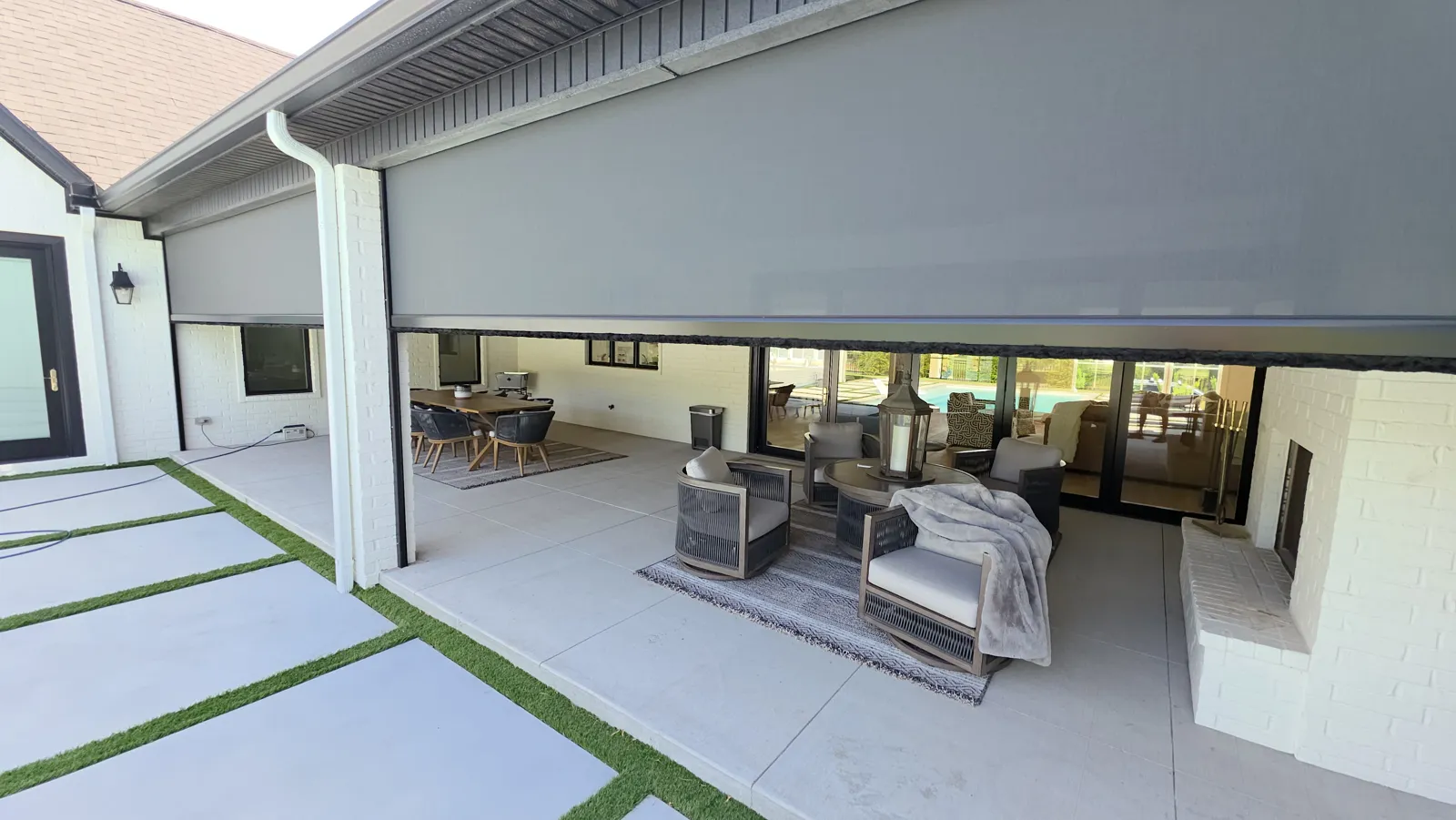 Gray screen lowered across the front of a covered patio with a sitting area on white painted brick in Clear Creek Patio Homes, Johnson, Arkansas