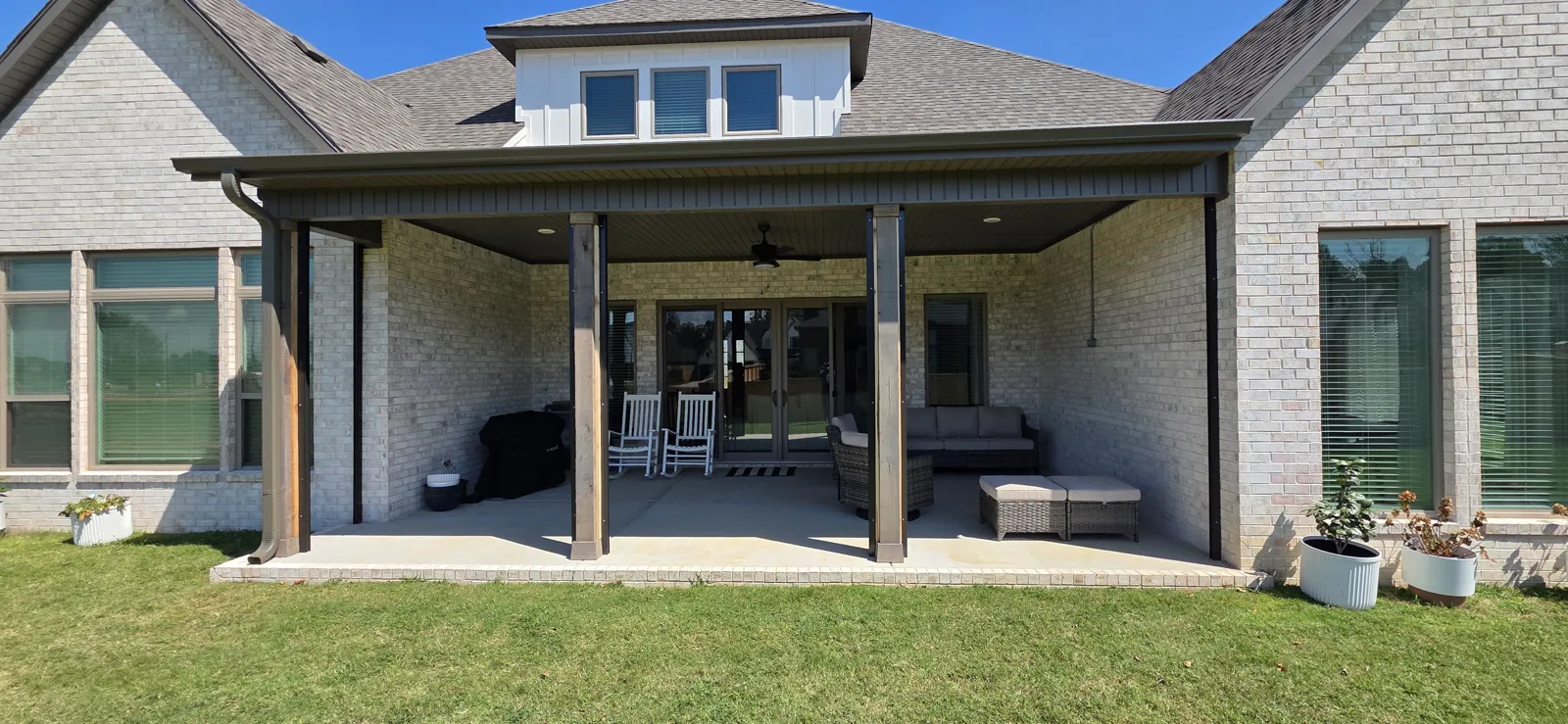 Covered back patio with dark posts and a ceiling fan on a brick house in Evening Star, Cave Springs, Arkansas