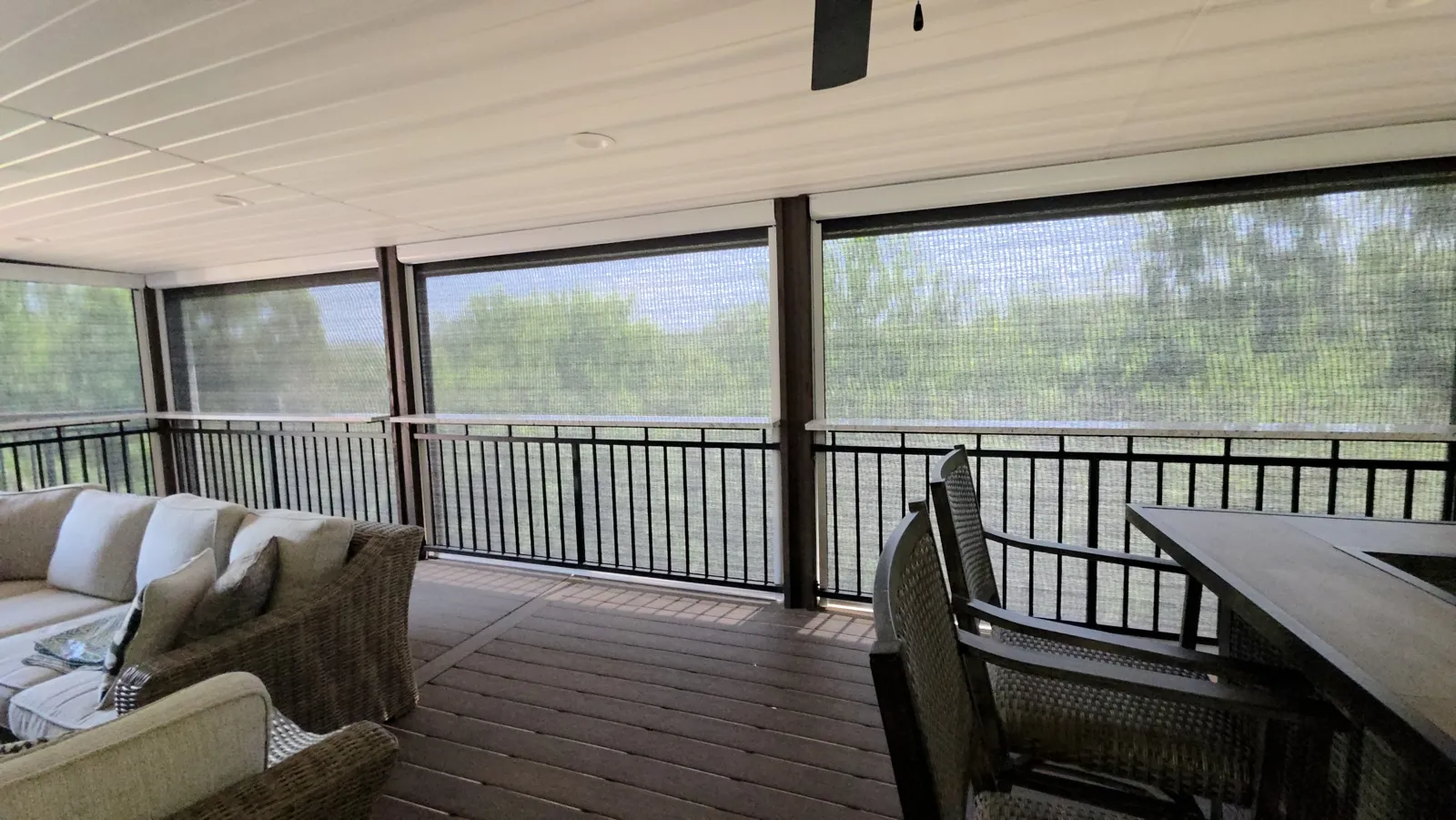 Light see-through mesh across a covered deck with black railing and a ceiling fan in Grand Pointe, Rogers, Arkansas