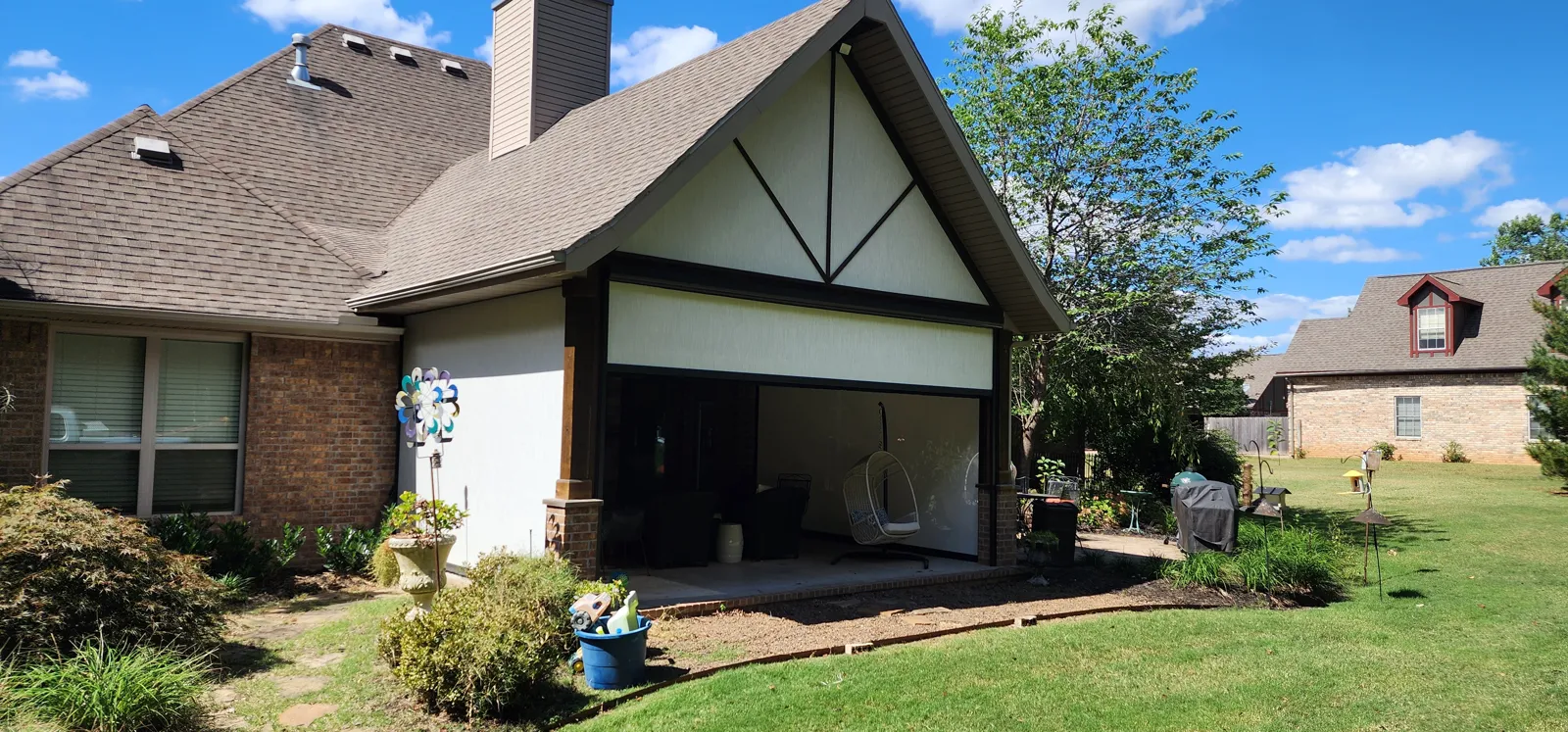Dark screen closed across a gabled covered back patio on a brick and stucco house in Hartsfield, Fayetteville, Arkansas
