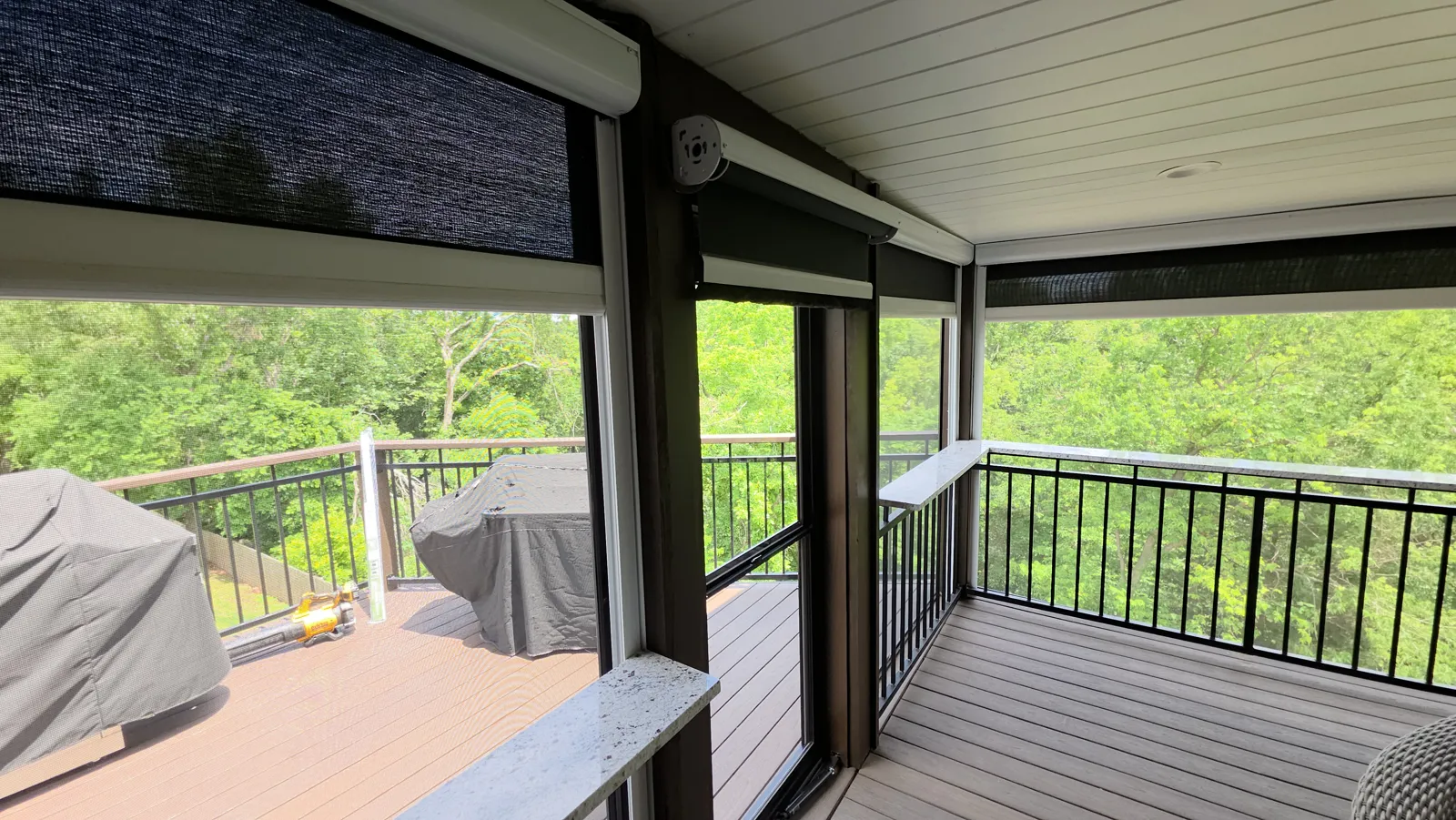 Dark mesh lowered on a covered deck with black railing and trees behind in Heathrow, Bentonville, Arkansas