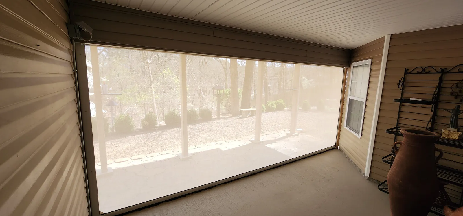White housing and light see-through retractable screen closed across a covered porch with vinyl siding in Lands End, Bella Vista, Arkansas