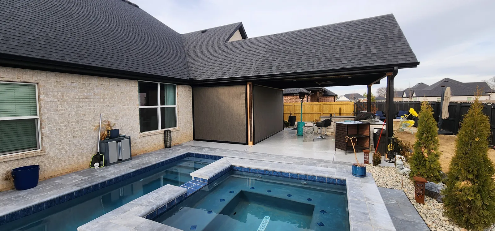 Dark brown retractable screen closed across a covered back patio next to a pool in Legacy Estates, Fayetteville, Arkansas