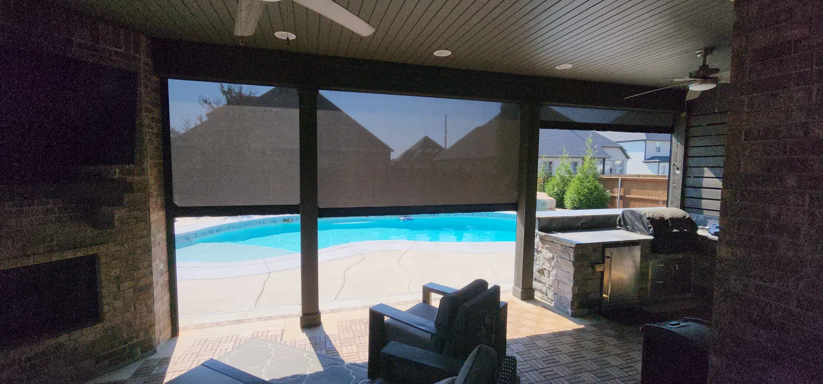 Inside view of a dark shade screen across a covered patio looking out to the pool in Lochmoor Club, Bentonville, Arkansas