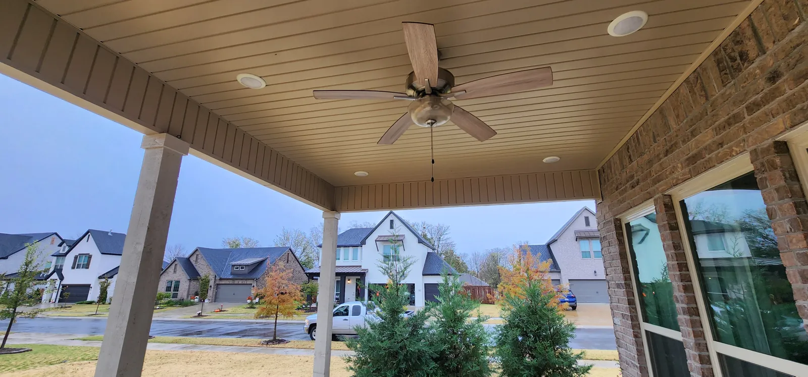 Covered porch with a ceiling fan and brick wall, street beyond in Magnolia Park, Fayetteville, Arkansas