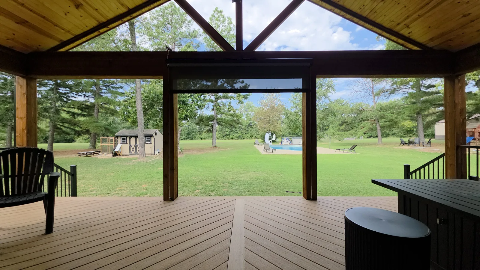 Timber-framed covered deck with cedar posts and beams looking out to a large lawn in Ozark Acres, Cave Springs, Arkansas