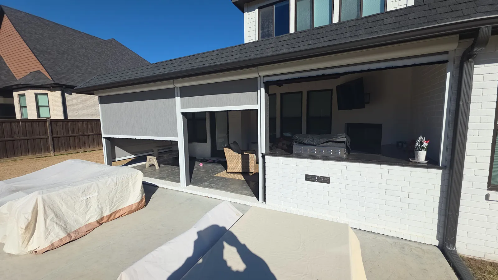 Gray screens on a covered patio with an outdoor kitchen on a white painted brick house in Providence, Fort Smith, Arkansas