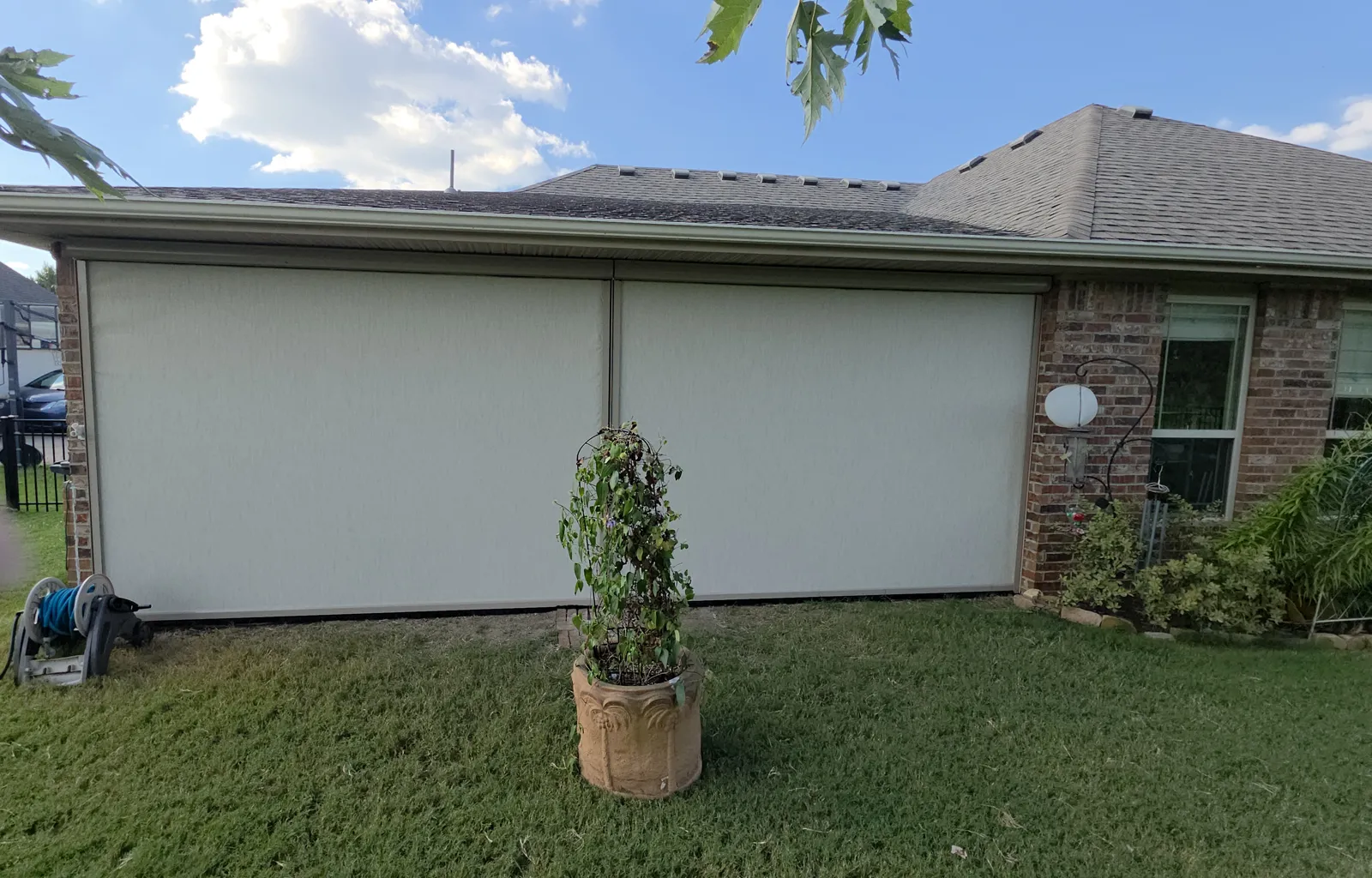 Two cream screens closed across a side patio opening on a brick house in Riviera Estates, Farmington, Arkansas