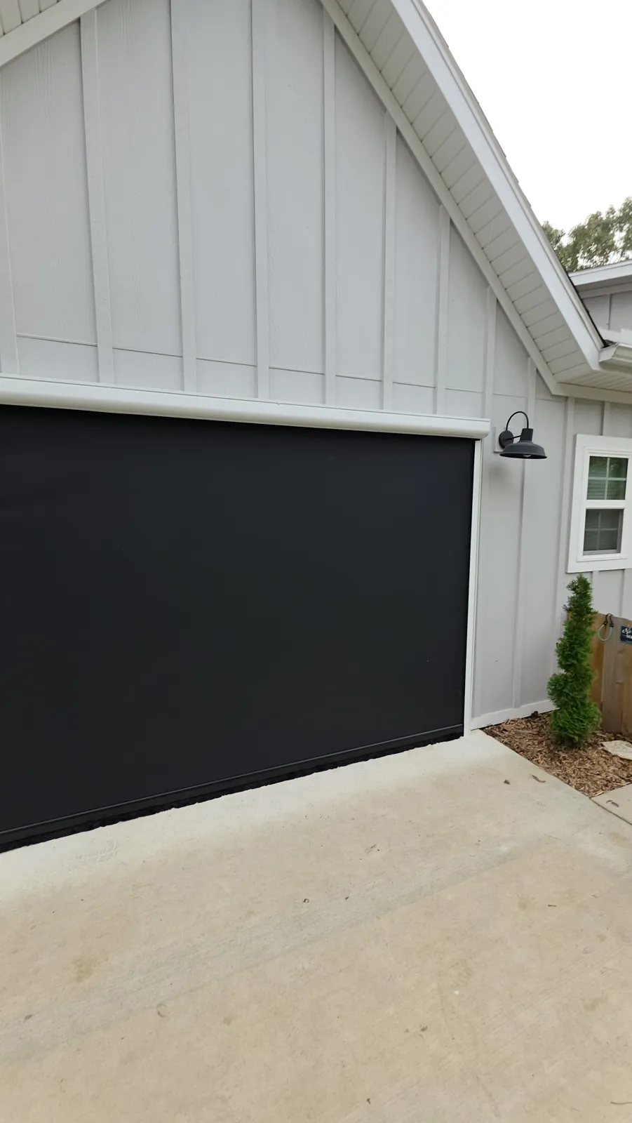 Black screen across a garage-size opening in white board-and-batten siding in Rosenheath, Bella Vista, Arkansas