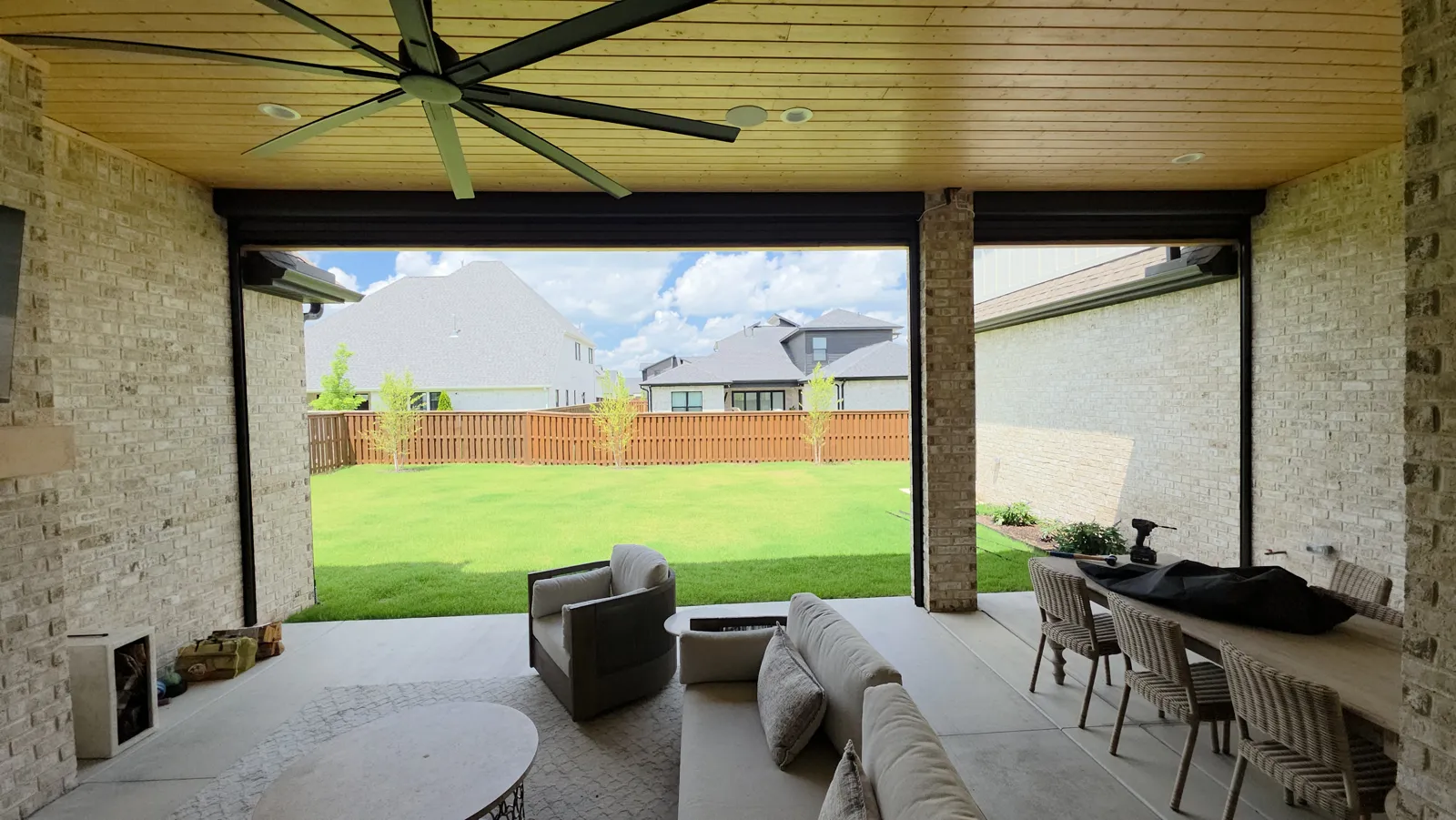 Covered back patio with a wood ceiling and ceiling fan looking out to a fenced lawn in Scissortail, Cave Springs, Arkansas