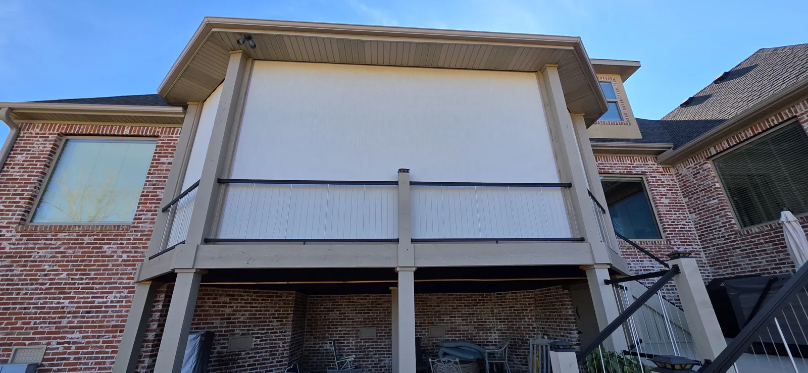 Light cream screen closed across an upper deck with cable railing on a red brick house in Shadow Valley, Rogers, Arkansas