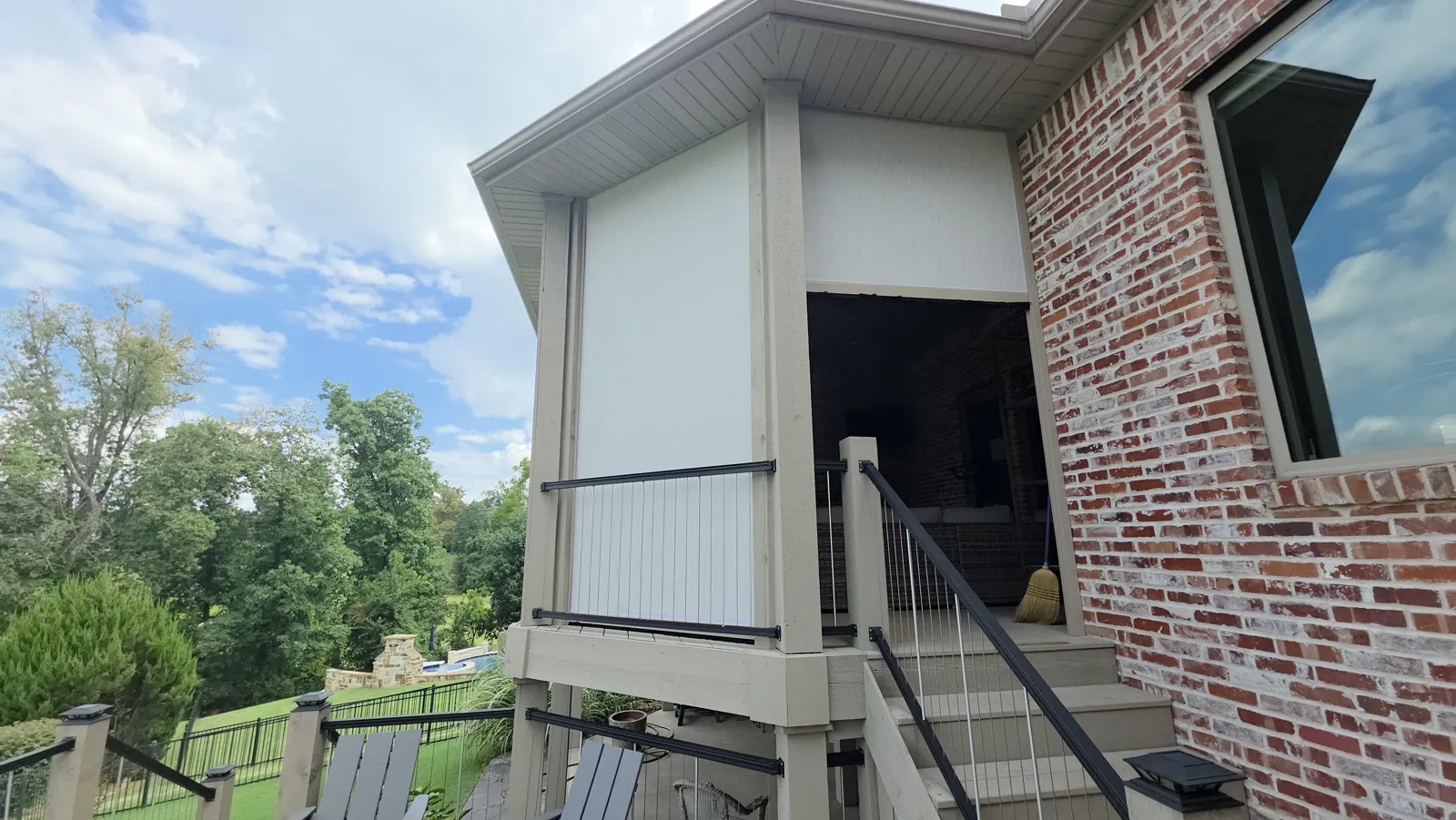 Cream screen closed on an upper deck corner beside a brick wall and trees in Shadow Valley, Rogers, Arkansas