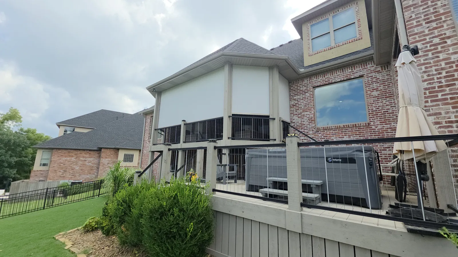 Cream screens across an elevated deck with railing on a red brick house in Shadow Valley, Rogers, Arkansas