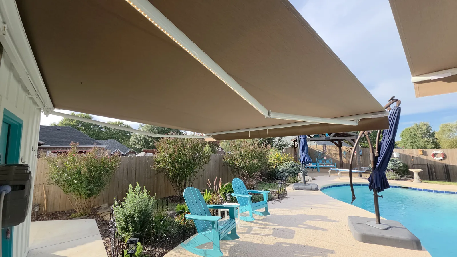 Tan fabric retractable awning with white arms and an LED strip over a pool patio in Silverthorne, Fayetteville, Arkansas