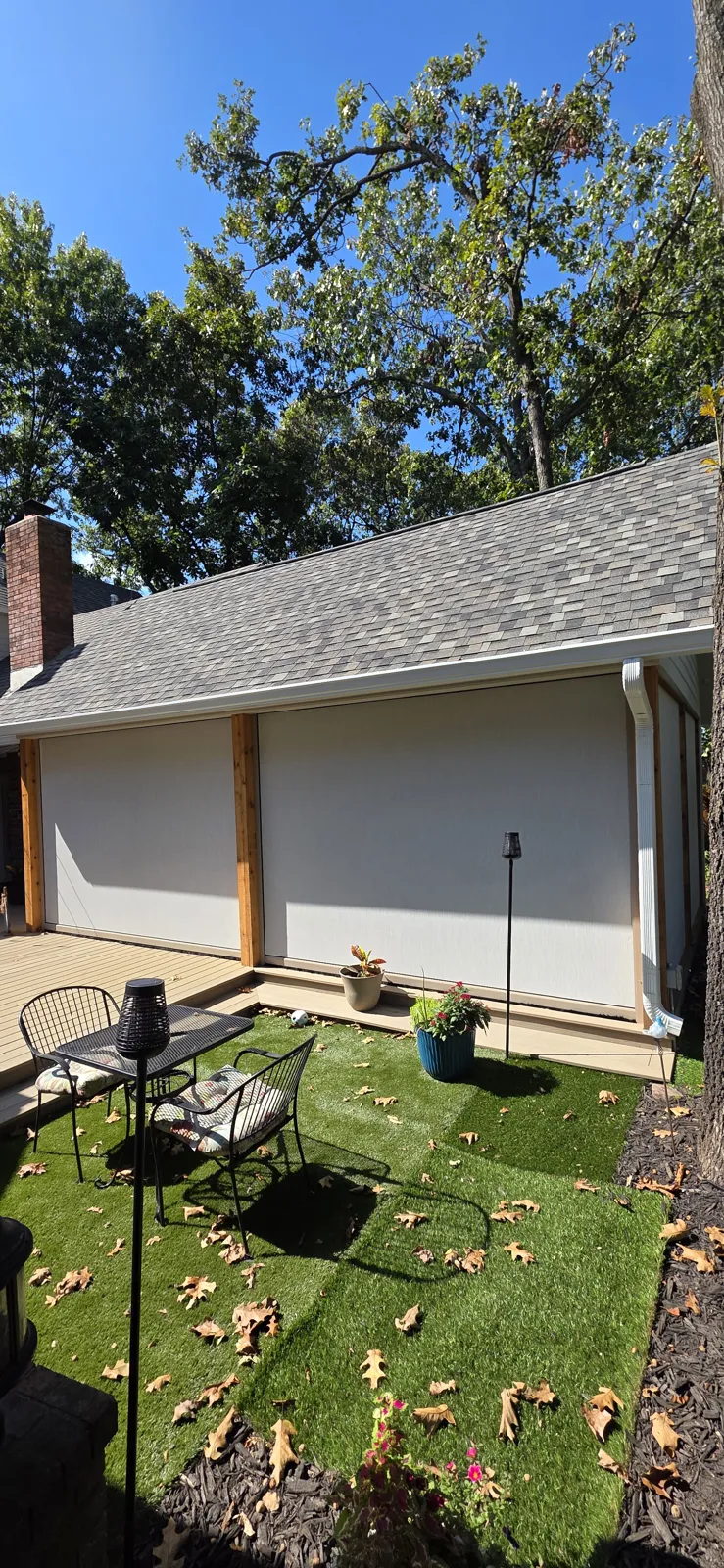 Cream screens closed across a small covered patio with a turf yard in Suttle Estates, Springdale, Arkansas