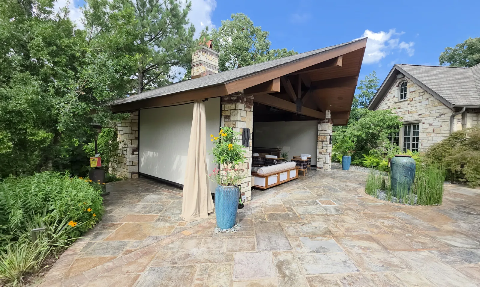 Cream screen closed on a stone-column pavilion with a flagstone patio and plantings in The Highlands on Riley Farm, Fort Smith, Arkansas