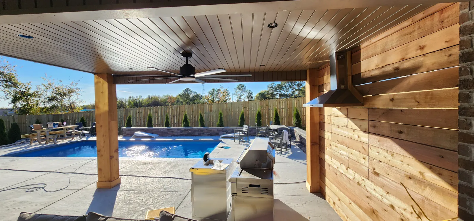 Cedar-post patio cover with a ceiling fan looking toward the pool in The Peaks, Rogers, Arkansas