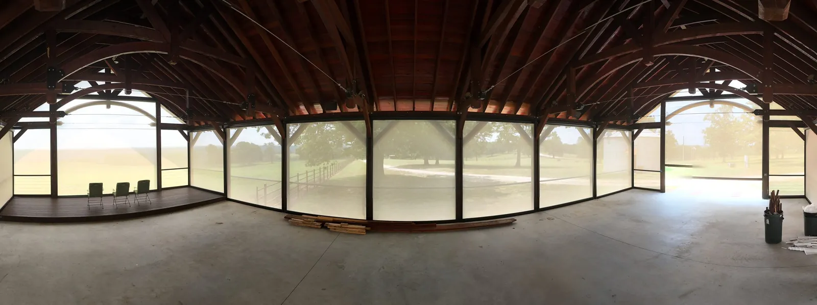 Inside a screened timber pavilion in Tilly, Arkansas showing motorized mesh screens filtering sunlight while keeping the open-air feel, installed by NWA Security Shutters