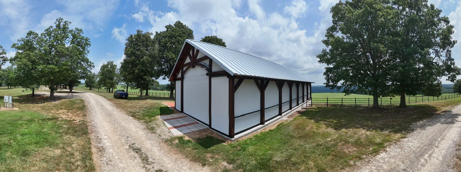 Exterior view of a timber frame event pavilion in Tilly, Arkansas fully enclosed with motorized retractable screens by NWA Security Shutters, metal roof and exposed wood beam construction