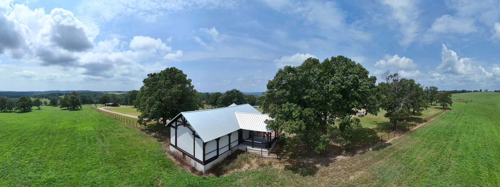 Panoramic interior view of a custom timber frame pavilion in Tilly, Arkansas with motorized retractable screens deployed on all sides, providing full insect protection while preserving views of the surrounding pasture