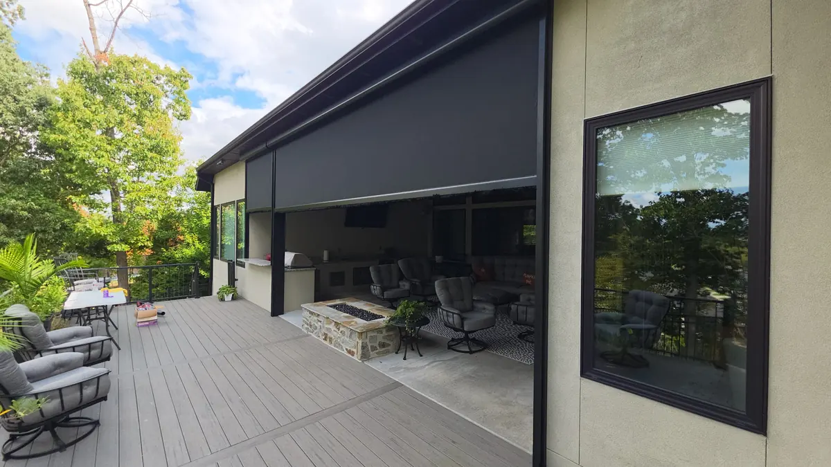 Motorized screen raised part way in Rogers, Arkansas, showing the outdoor kitchen and fire pit under the cover